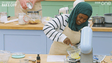 British Bake Off contestant smiling while hand mixing dough