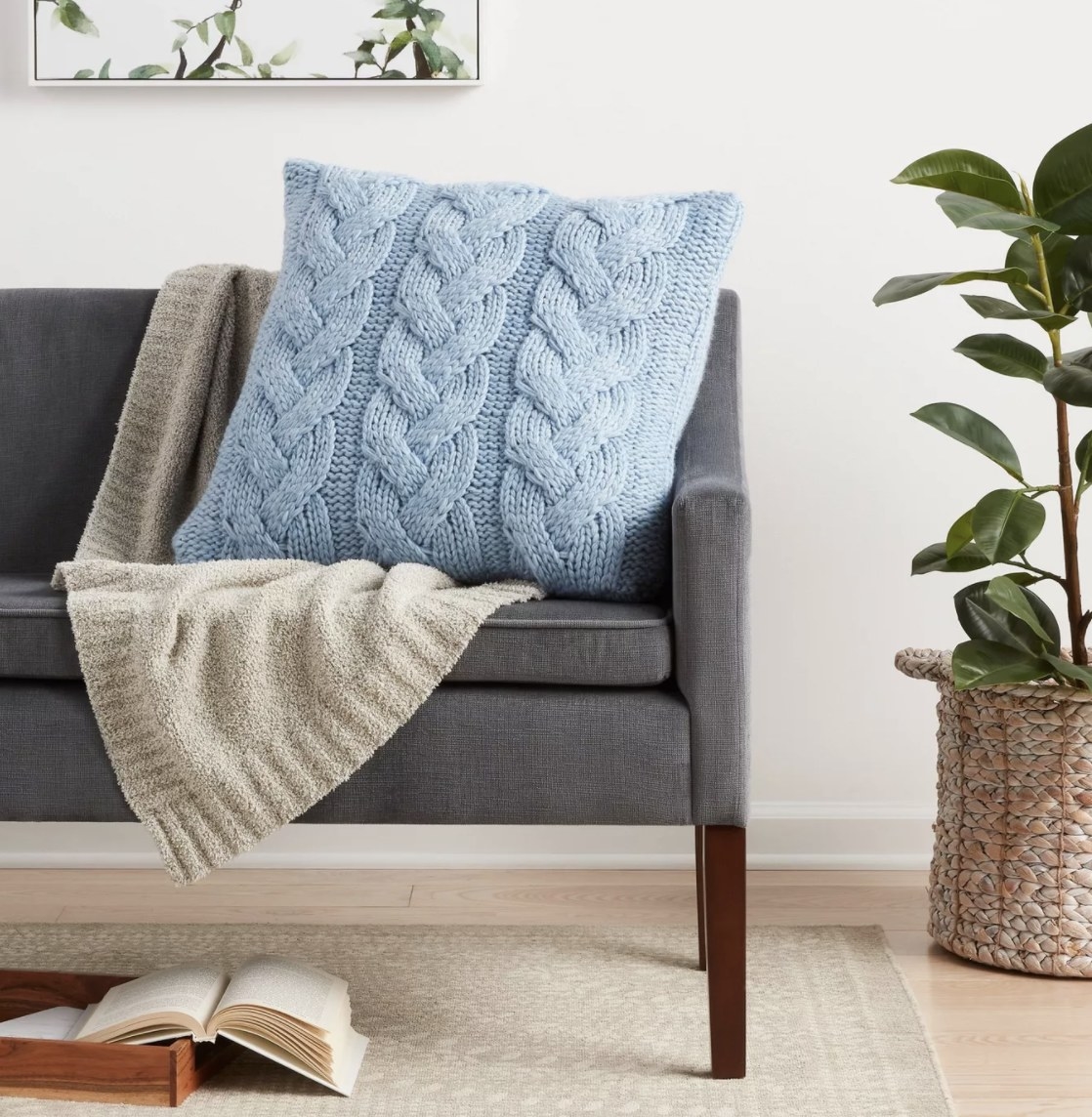 The light blue cable knit pillow is on a grey couch