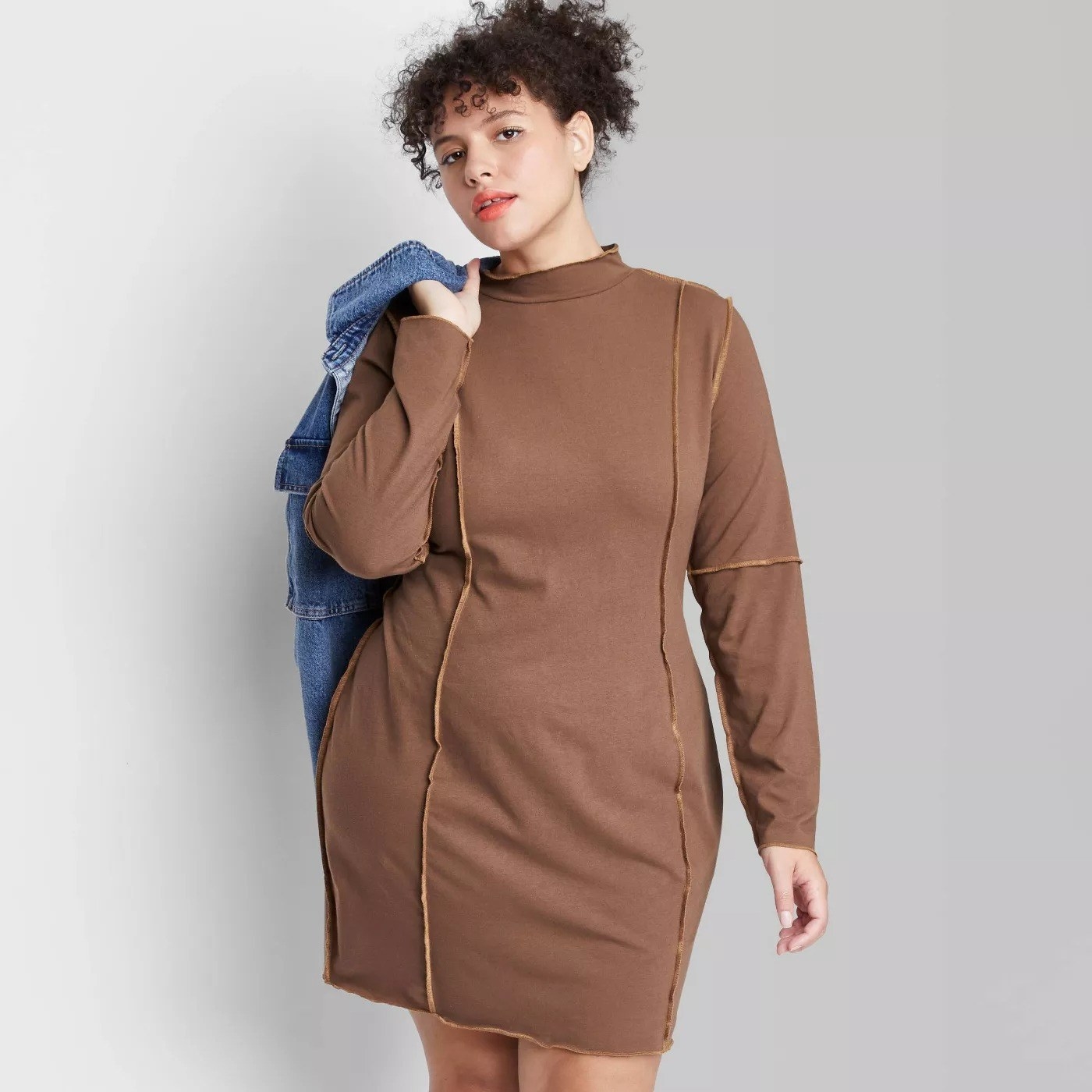 Model wearing long sleeve mocha colored dress, stops above the knee