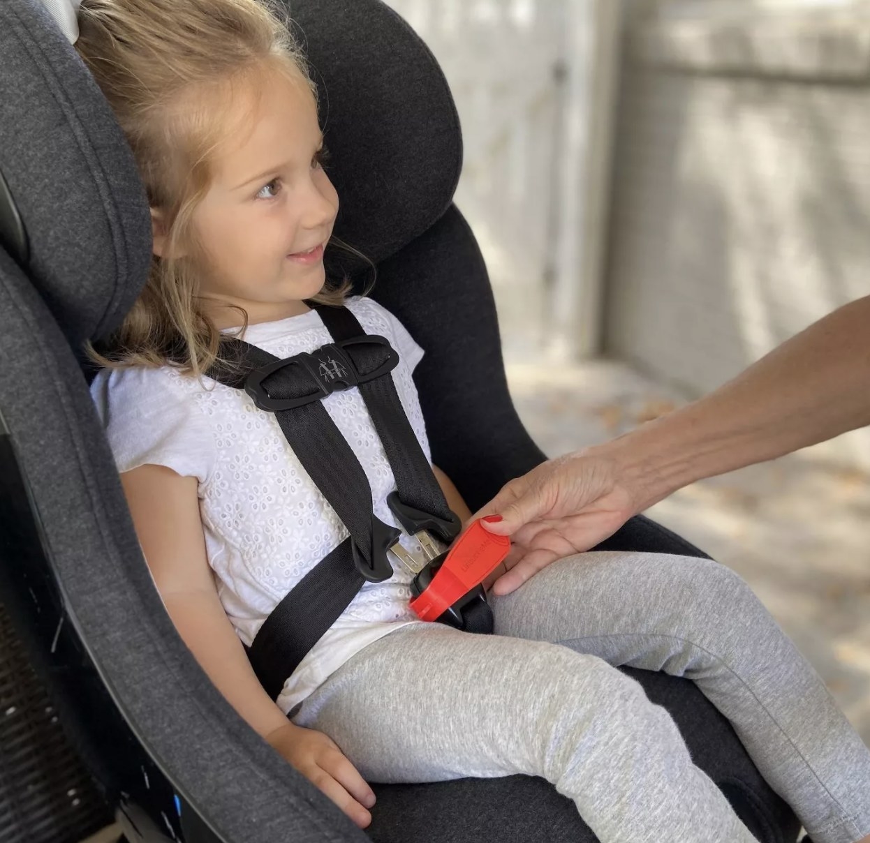 Kid in car seat and parent using seat buckle release tool