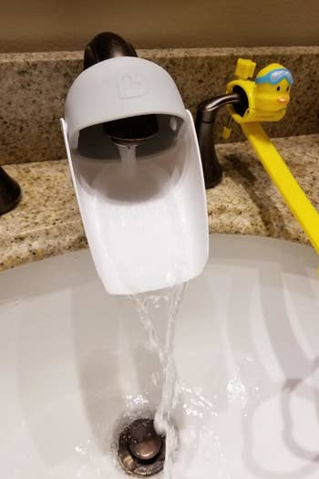 a reviewer's installed faucet extender with water coming out