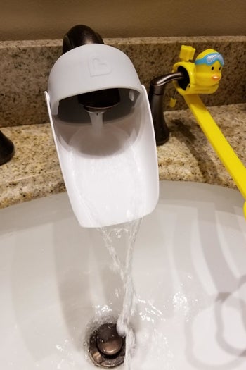 a reviewer photo of the installed faucet extender with water coming out