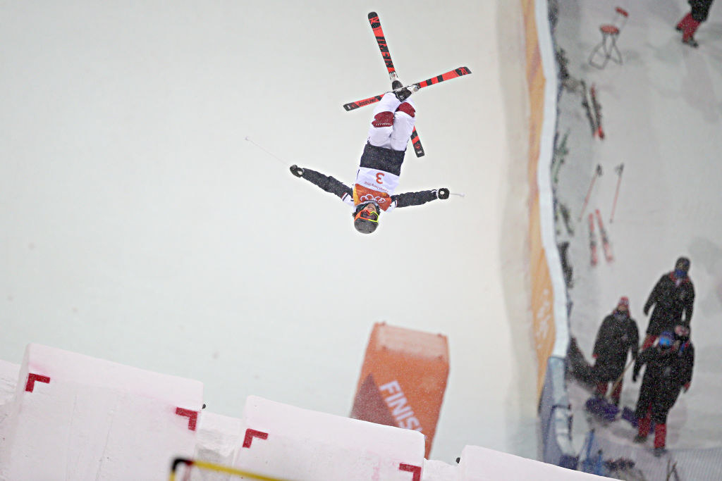 A skier flips midair during the moguls event