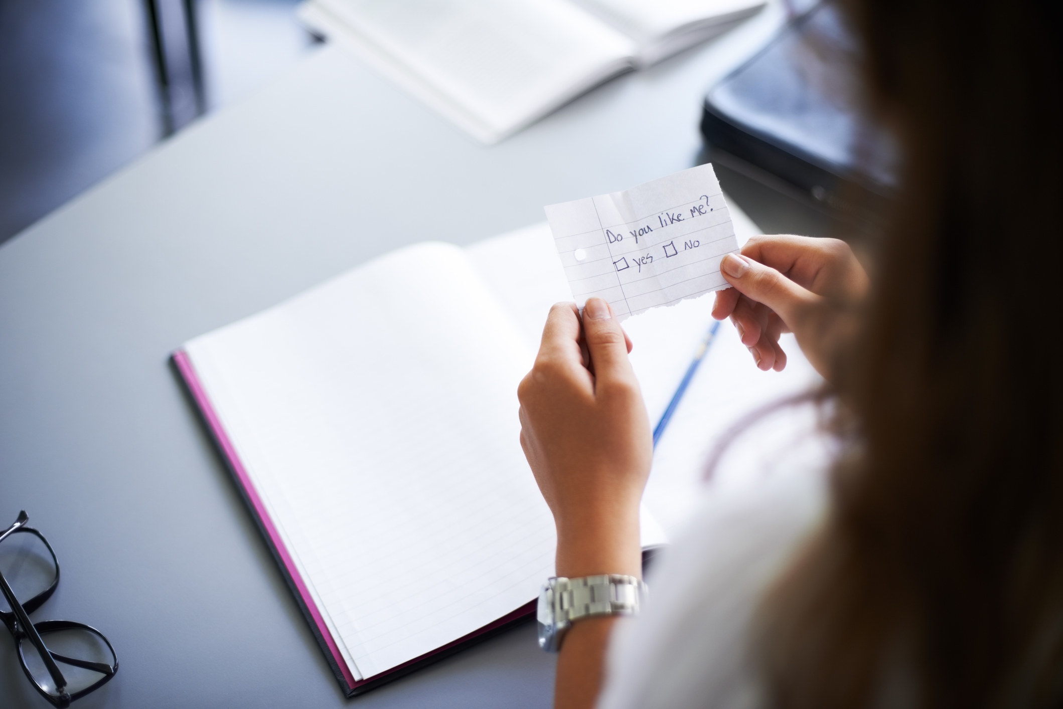 A stock image of someone at a desk holding a note that reads, &quot;Do you like me?&quot;