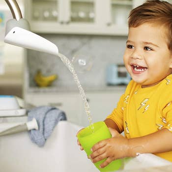 a child model getting water from a sink with the faucet extender installed