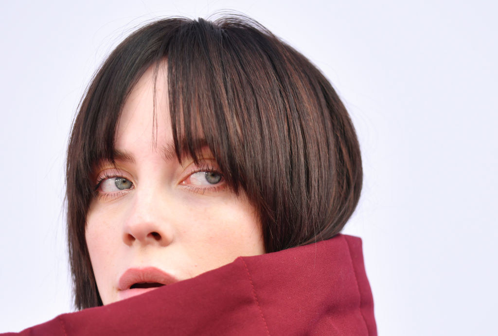 Close up of Billie Eilish with red coat of collar pulled high
