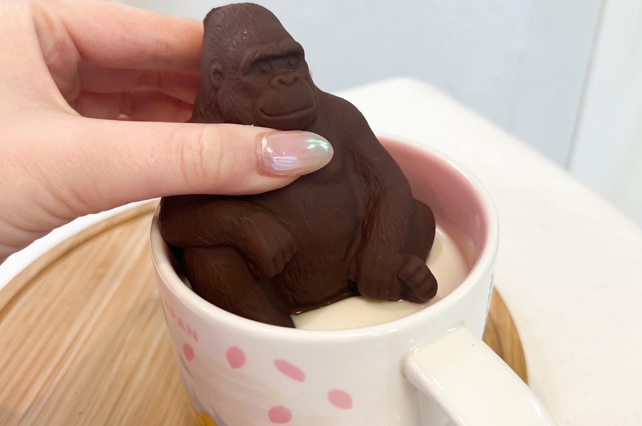 ゴリラ形の茶色いチョコレートをホットミルクにつけている様子
