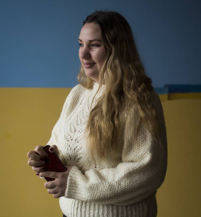 A woman in a sweater stands and holds her cellphone