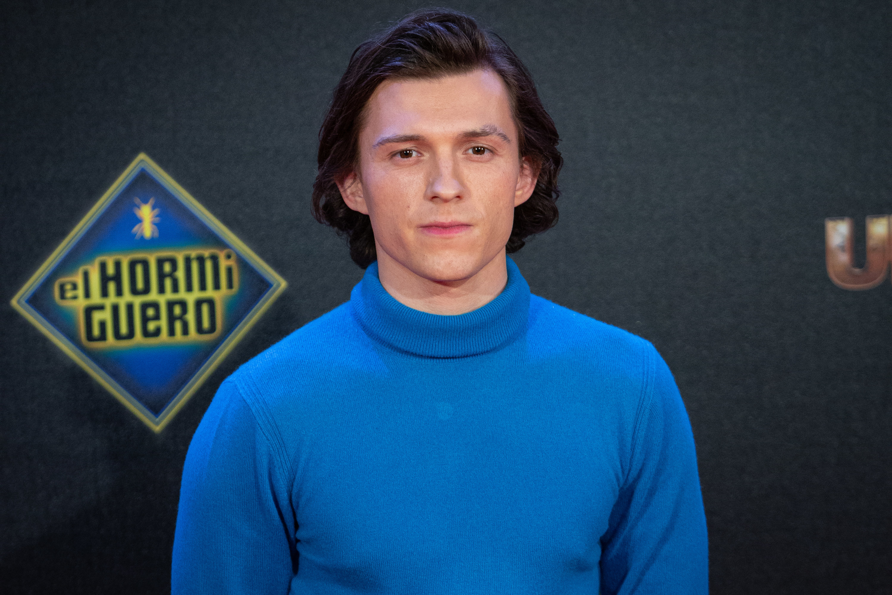 Tom poses for a picture while wearing a turtleneck