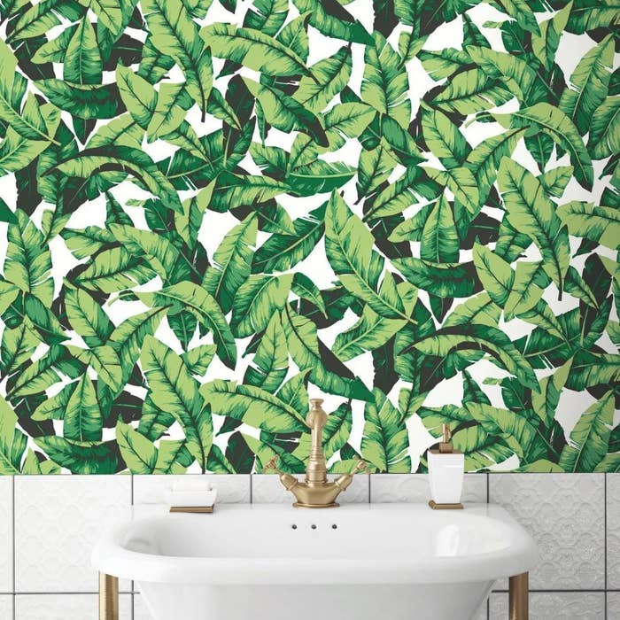 A green palm leaf peel and stick wallpaper on the wall of a bathroom