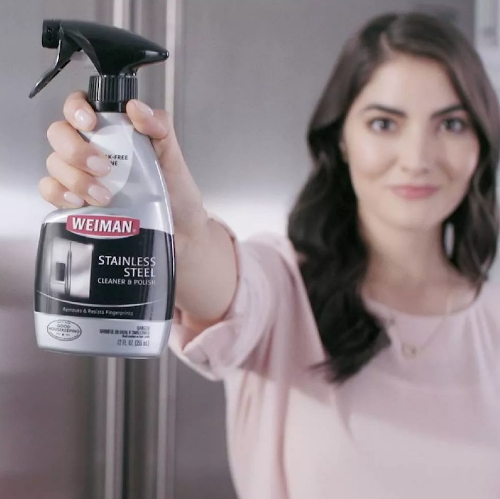 A model holding a bottle of stainless steel cleaner and polisher