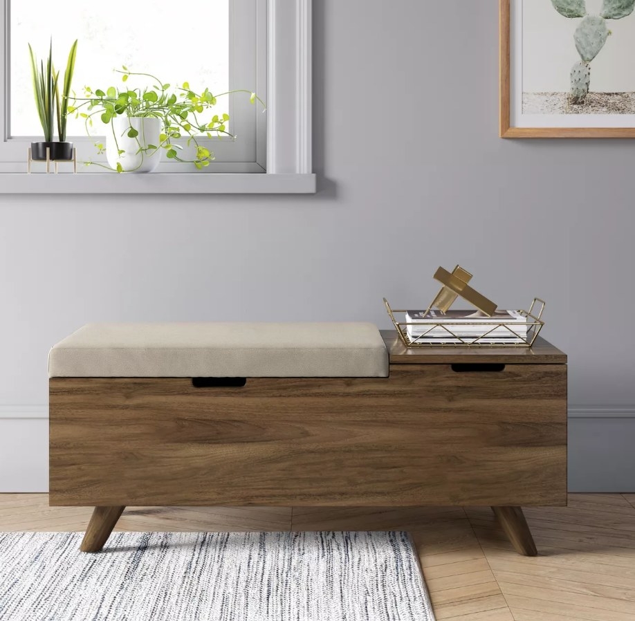 A wood and beige upholstered storage bench