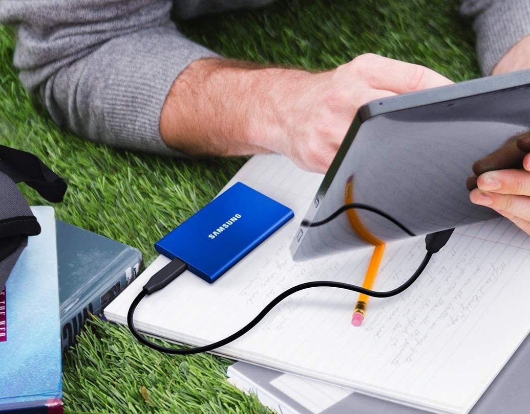 An external hard drive plugged into a tablet that someone is holding