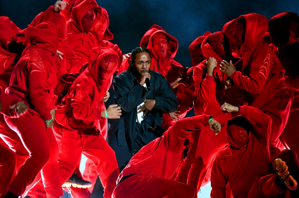 Kendrick in all black surrounded by dancers in all red