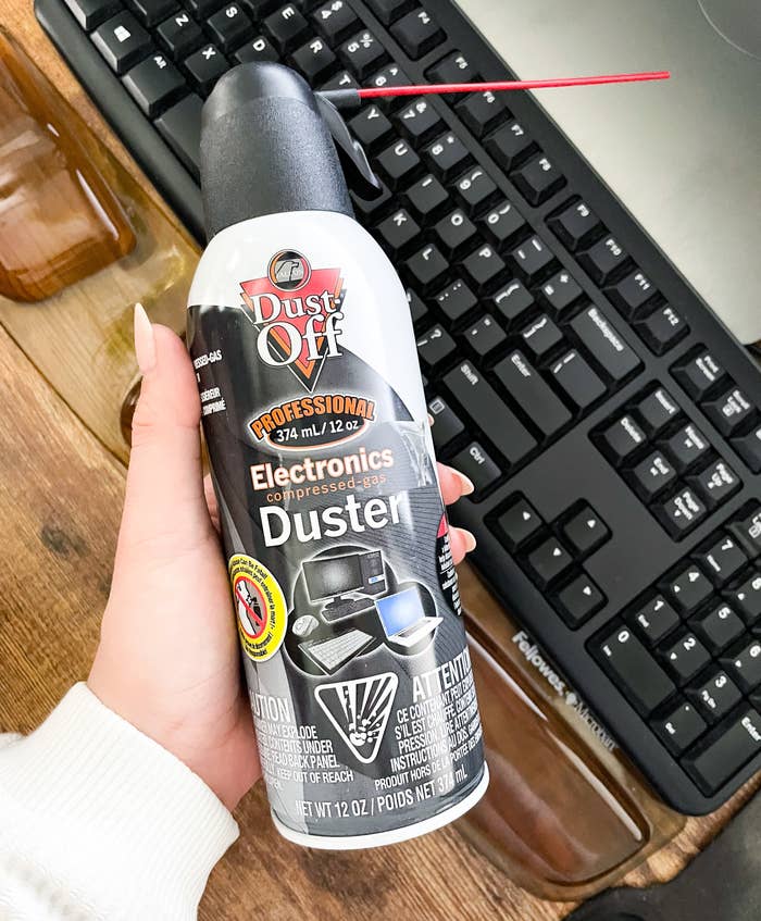 Someone holding the gas duster against a keyboard