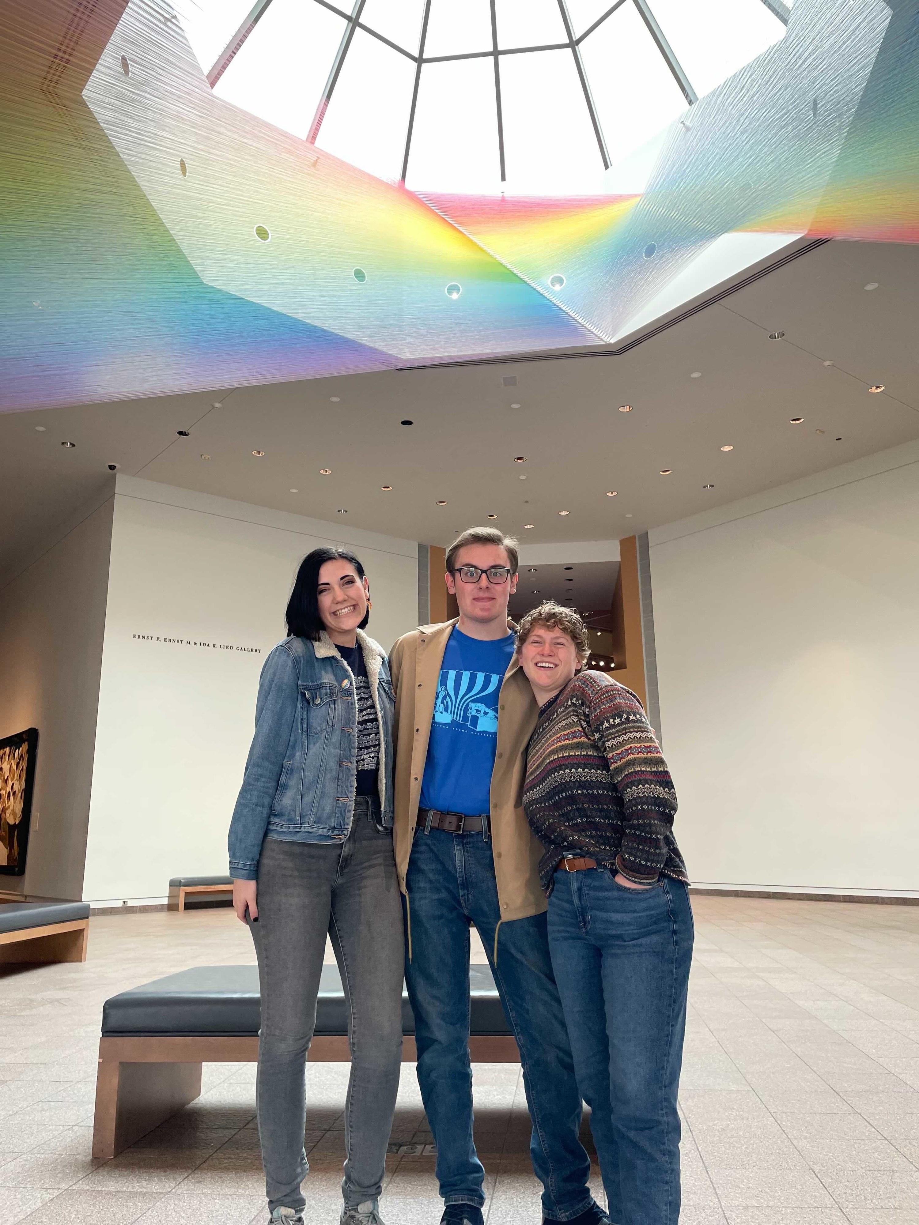 Three people smiling for a picture in an art gallery 