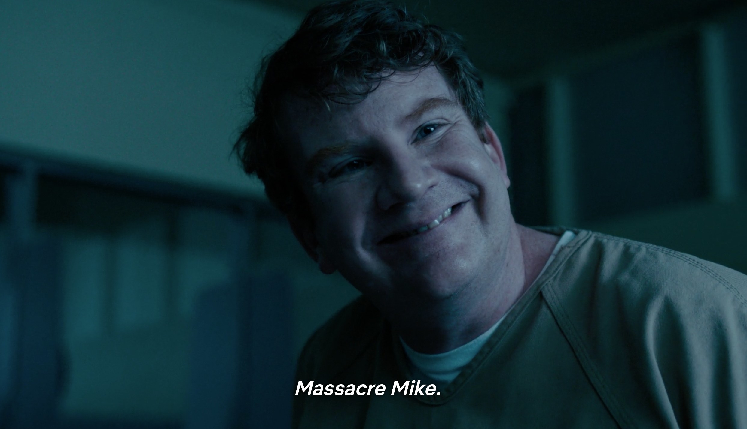 An eerie looking male prisoner named Massacre Mike smiles with his head tilted