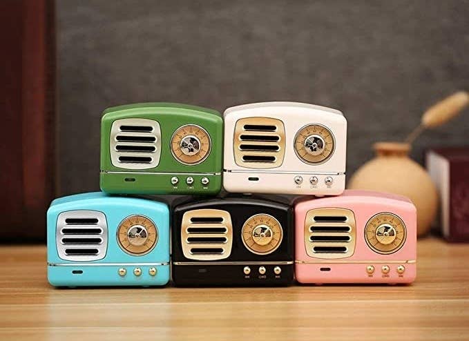 Five bluetooth speakers in green, white, blue, black, and pink