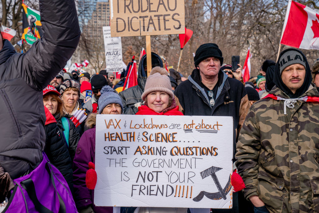 a protester holds a sign saying that lockdowns aren&#x27;t about health and science