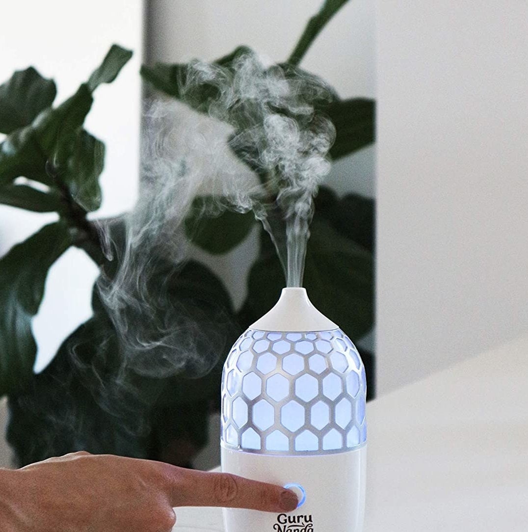 A person pressing the power button on the diffuser