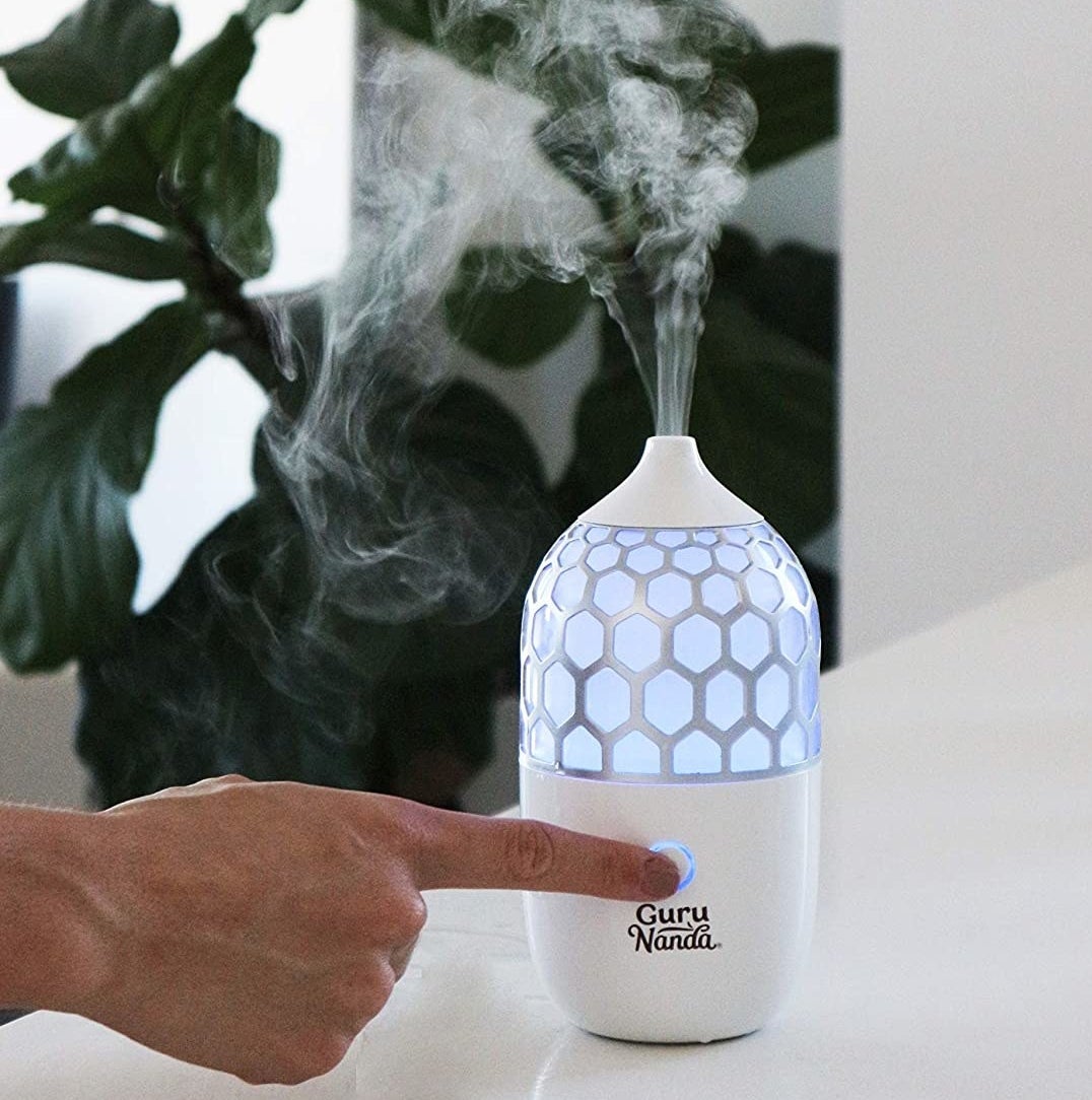 A person pressing the power button on the diffuser