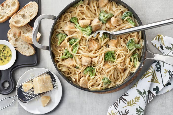 Chicken and broccoli pasta on serving dish beside bread