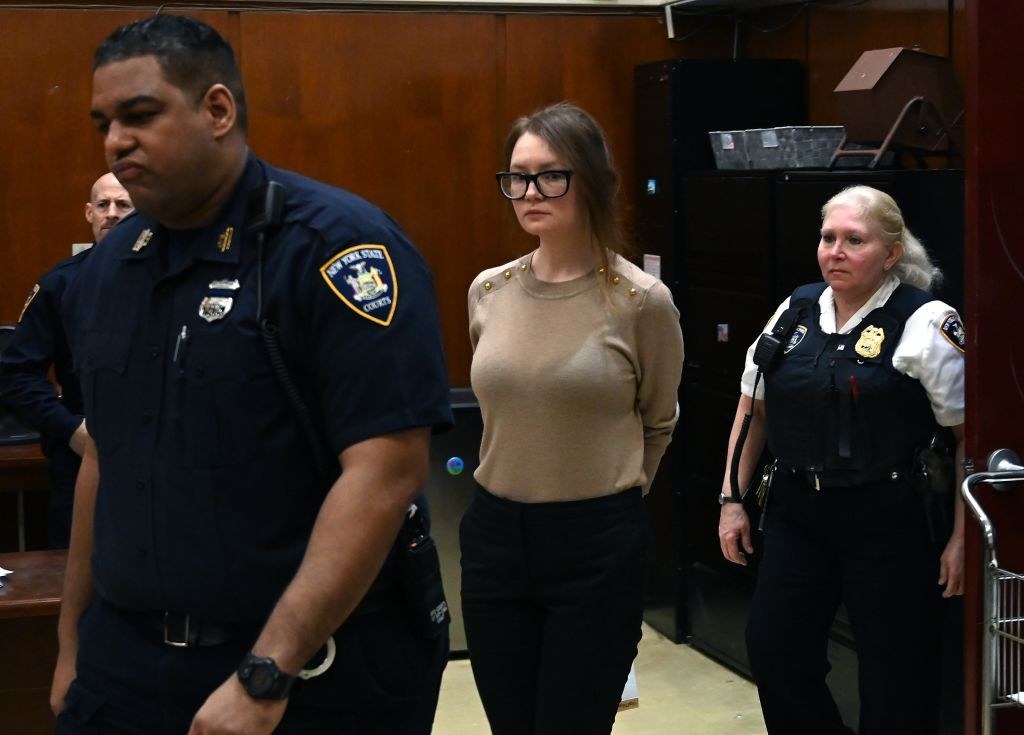 Anna in handcuff walking in court while being escorted by two officers