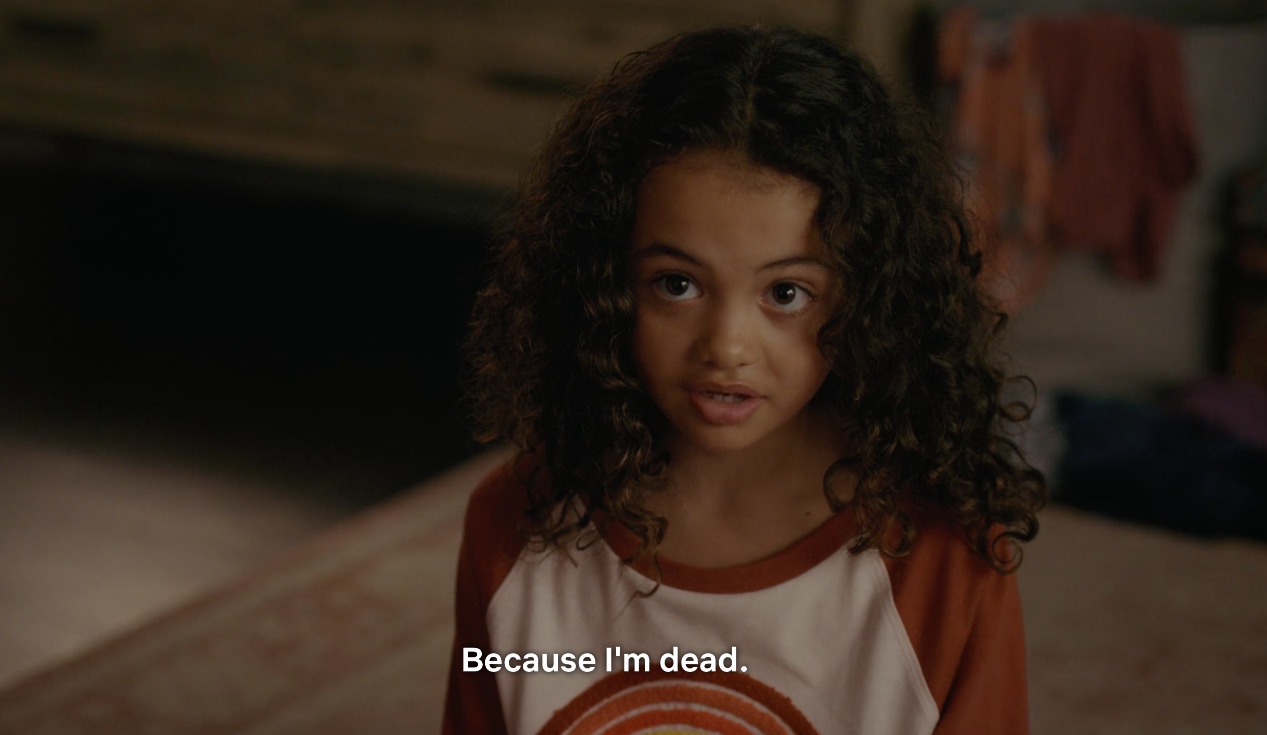 A young girl with curly hair staring up at her mom saying, &quot;Because I&#x27;m dead&quot;