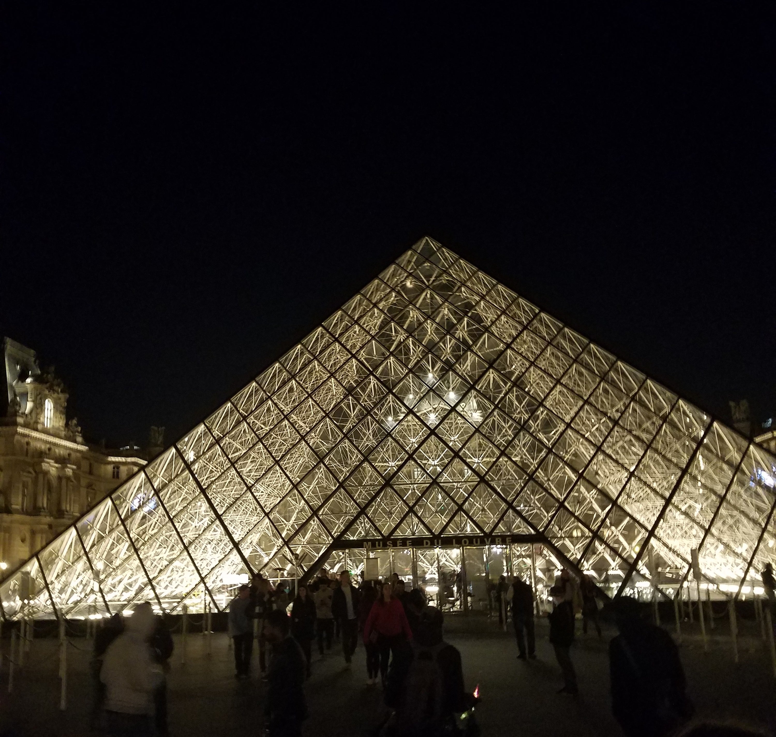 Visitors walking into the pyramid entrance at the Louvre