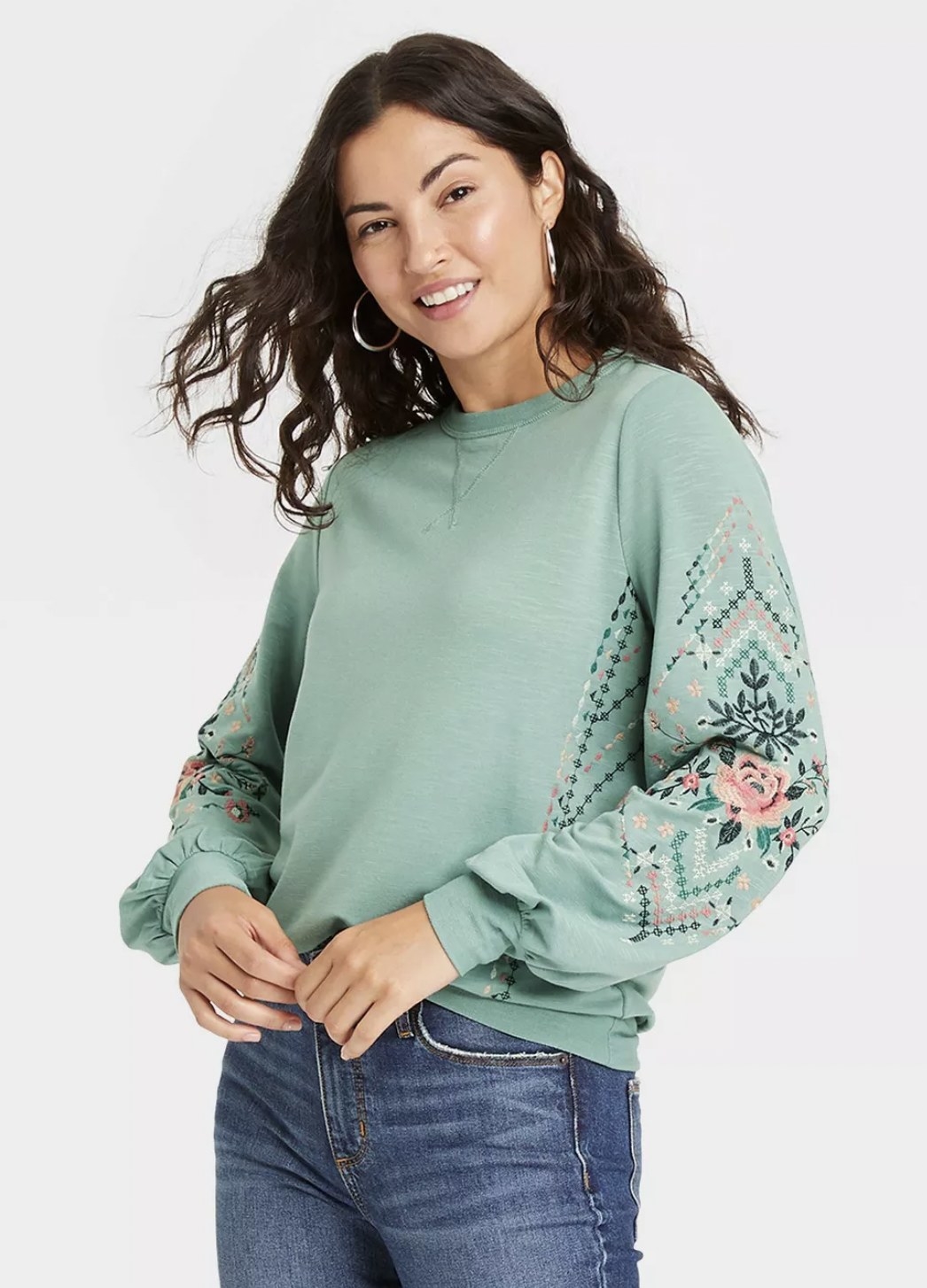 front view of model wearing the sweater in mint with green, pink, and white floral details on the elbows