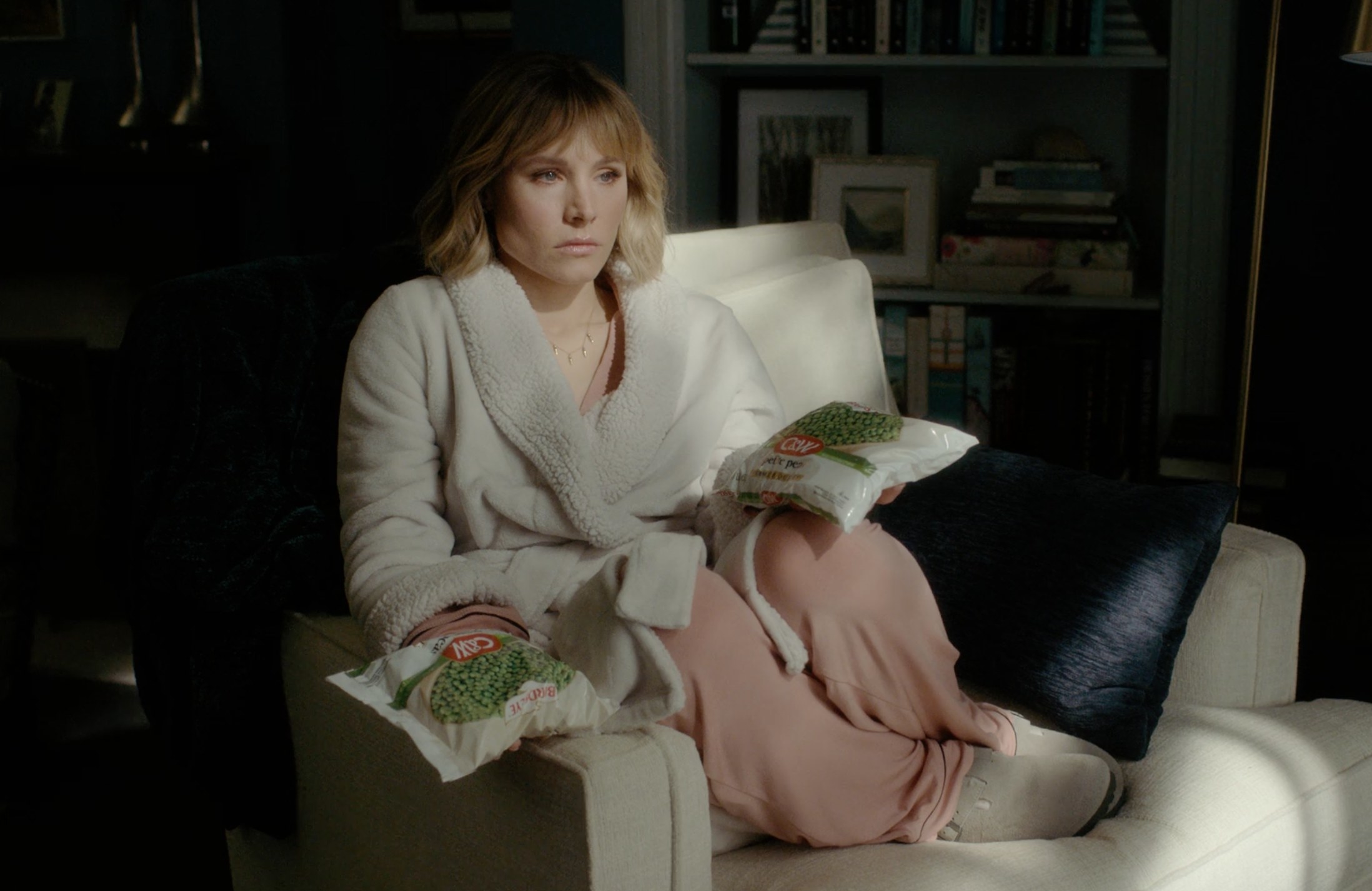 Kristen Bell with bags of frozen peas in her hands as she sits in her chair by the window in &quot;The Woman In The House&quot;