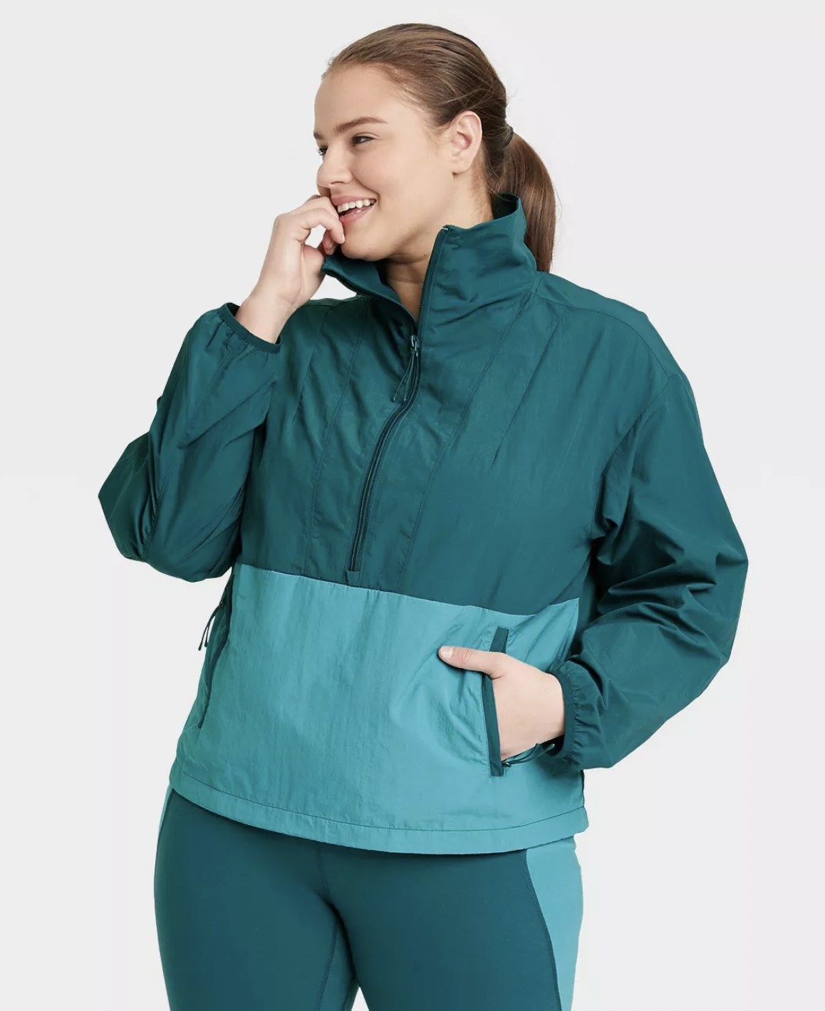 model wearing the windbreaker in teal and turquoise