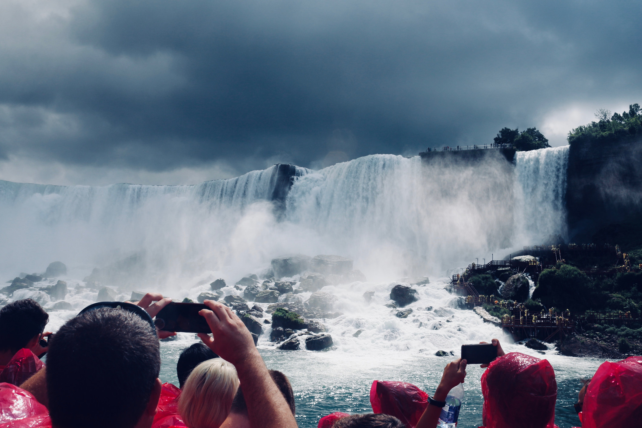 Tourists taking photos of the falls while on a boat tour