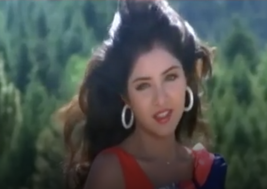 Bharti singing in a red dress with hoop earrings