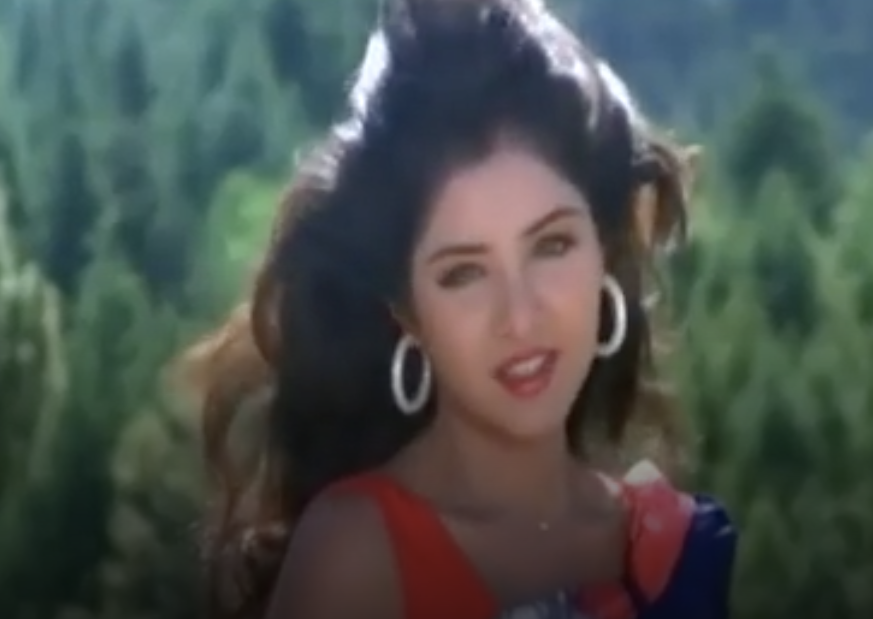 Bharti singing in a red dress with hoop earrings