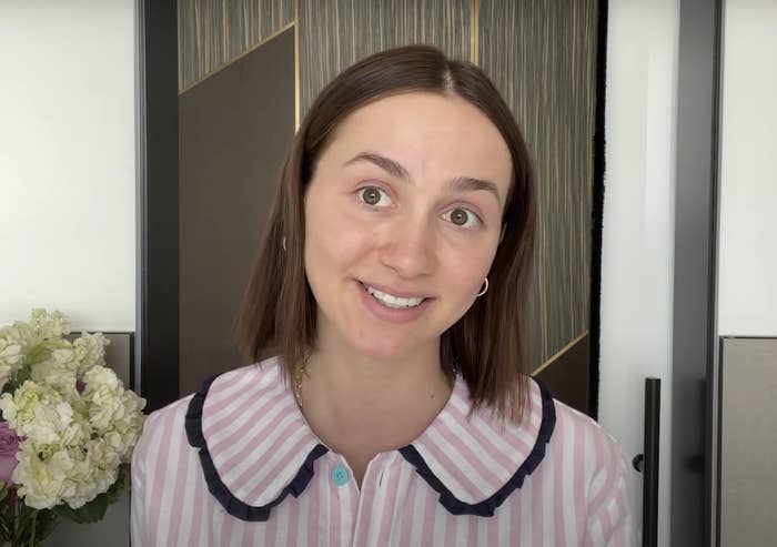 Maude smiles while sitting in her pajamas about to do her makeup