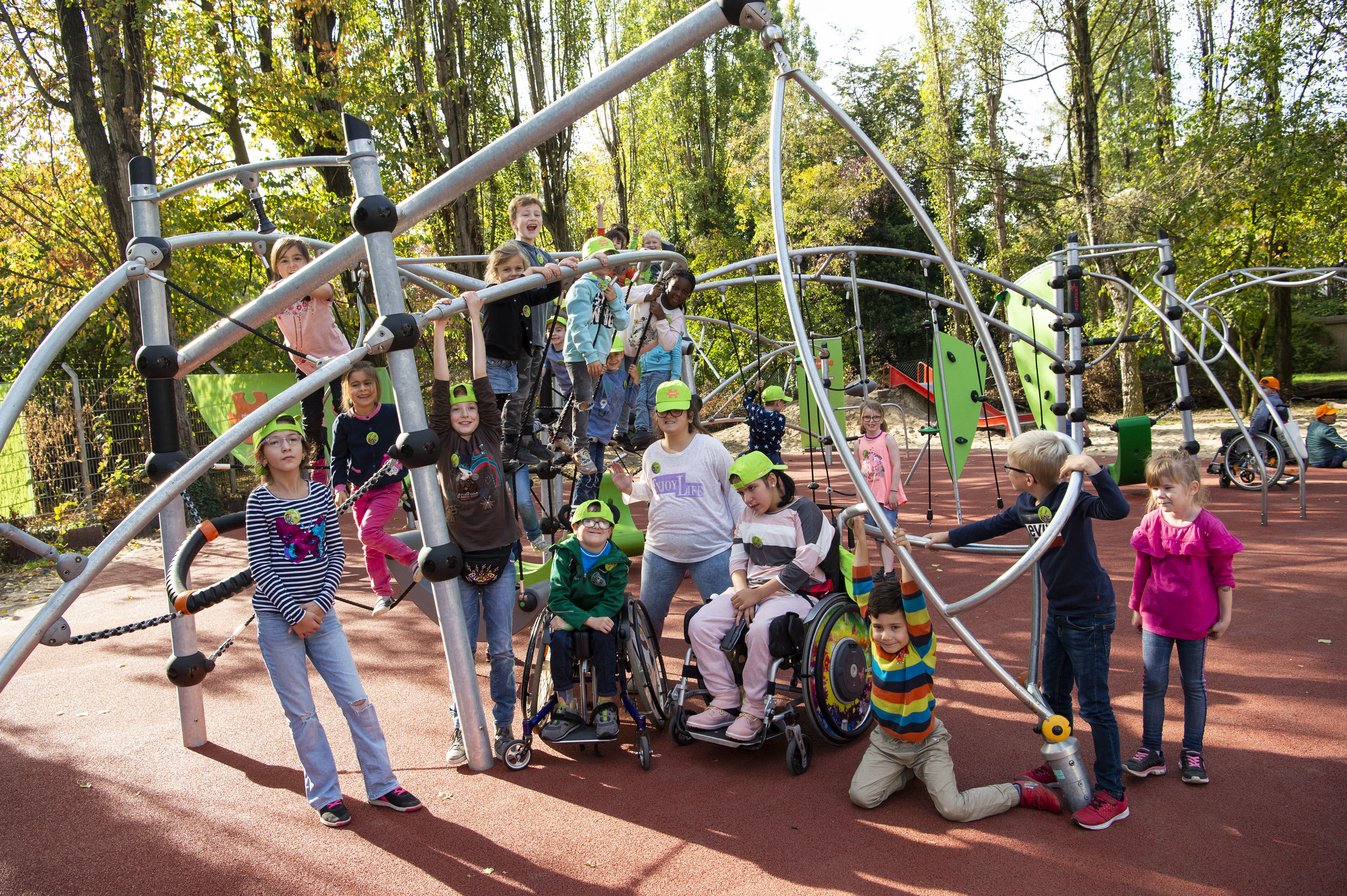 A group of children posing in front of an elaborate playground full of swings and ropes.
