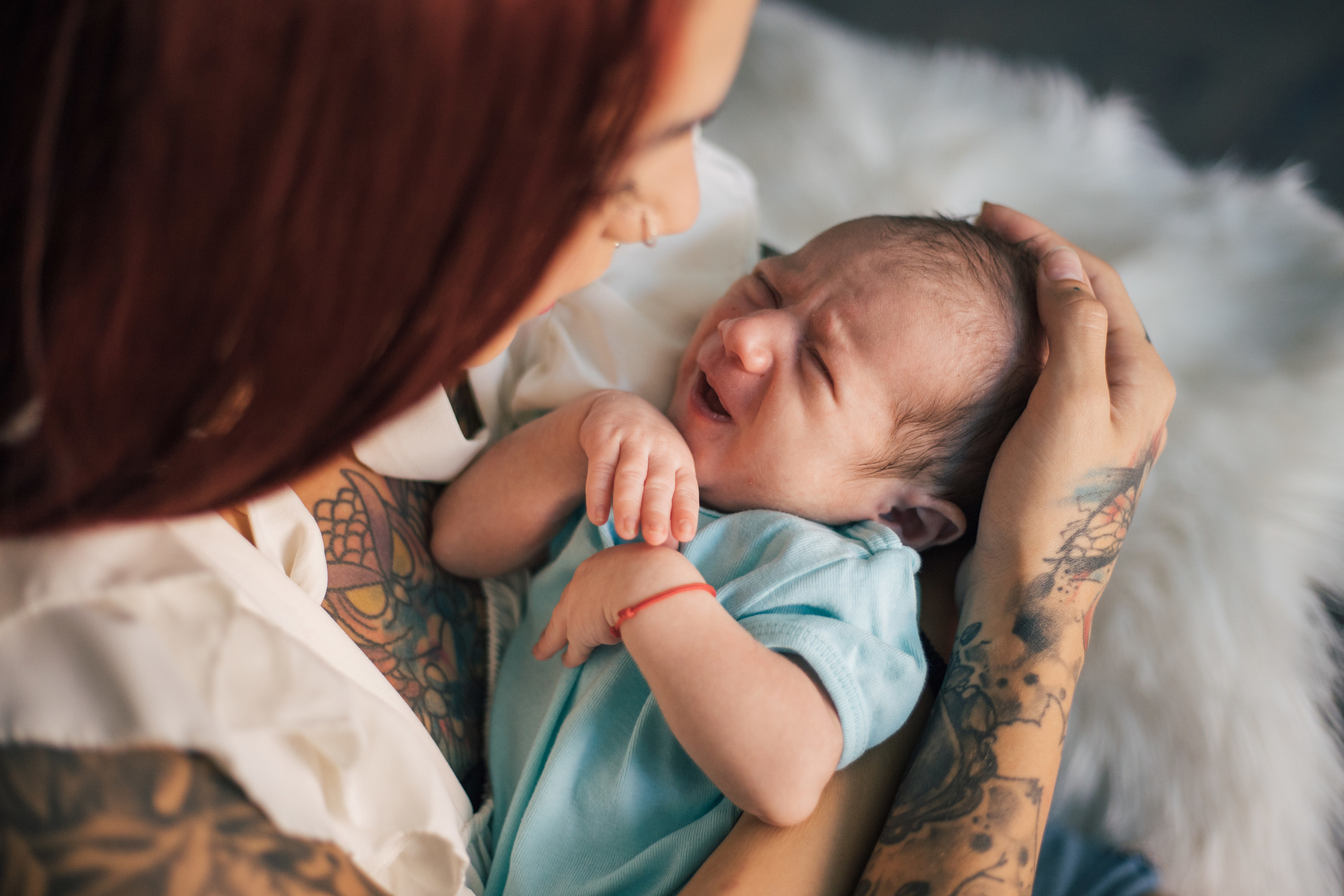 Tattooed woman holding a newborn close to her chest