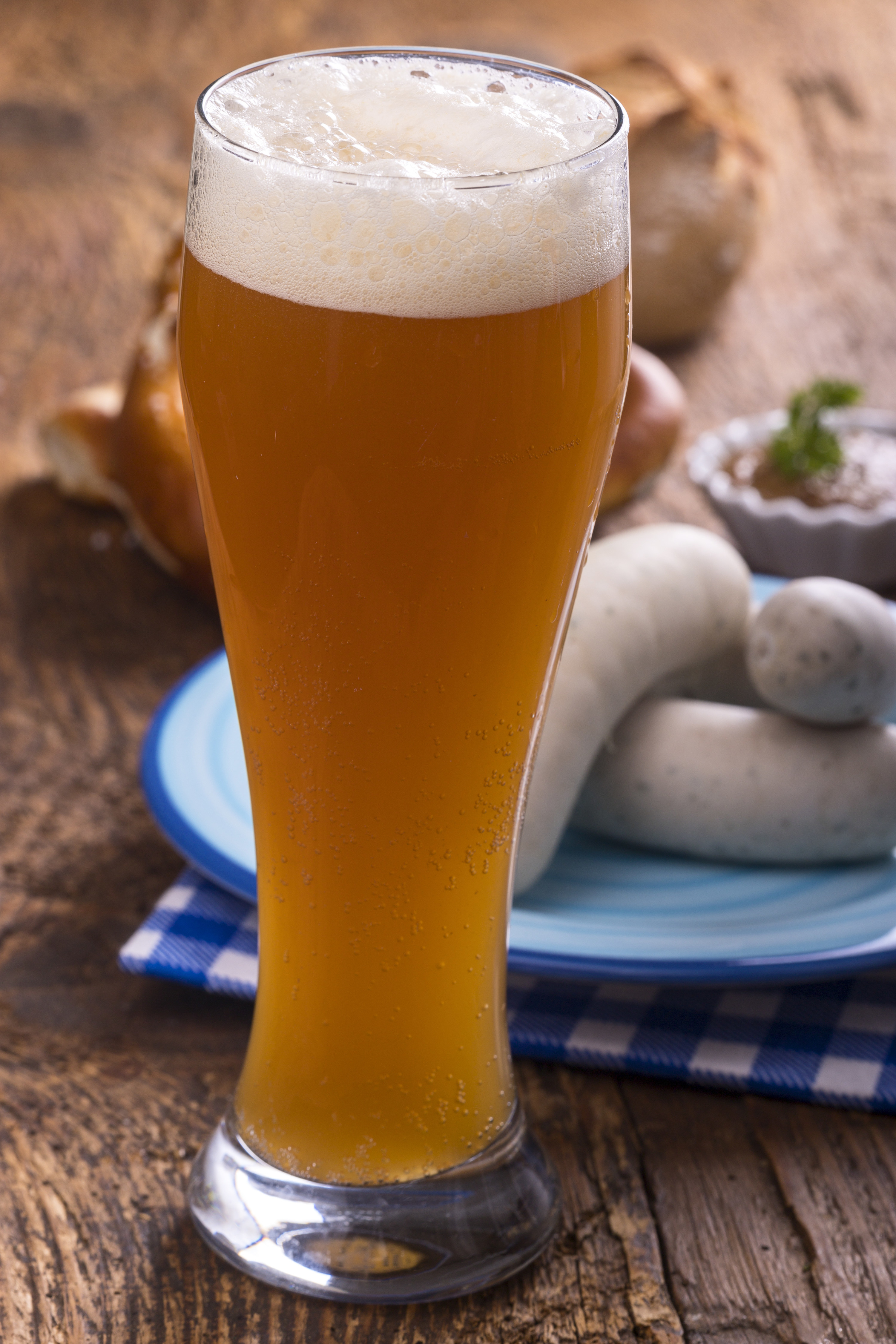 Glass of traditional German wheat beer, with checkered blue towelette in background