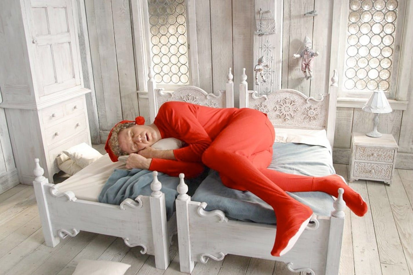 Will Ferrell as Buddy the Elf in Elf curled up across two beds sideways in the fetal position