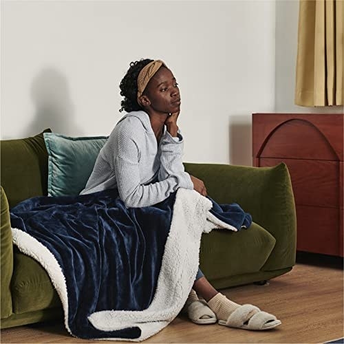 model sitting on sofa with the faux sherpa blanket