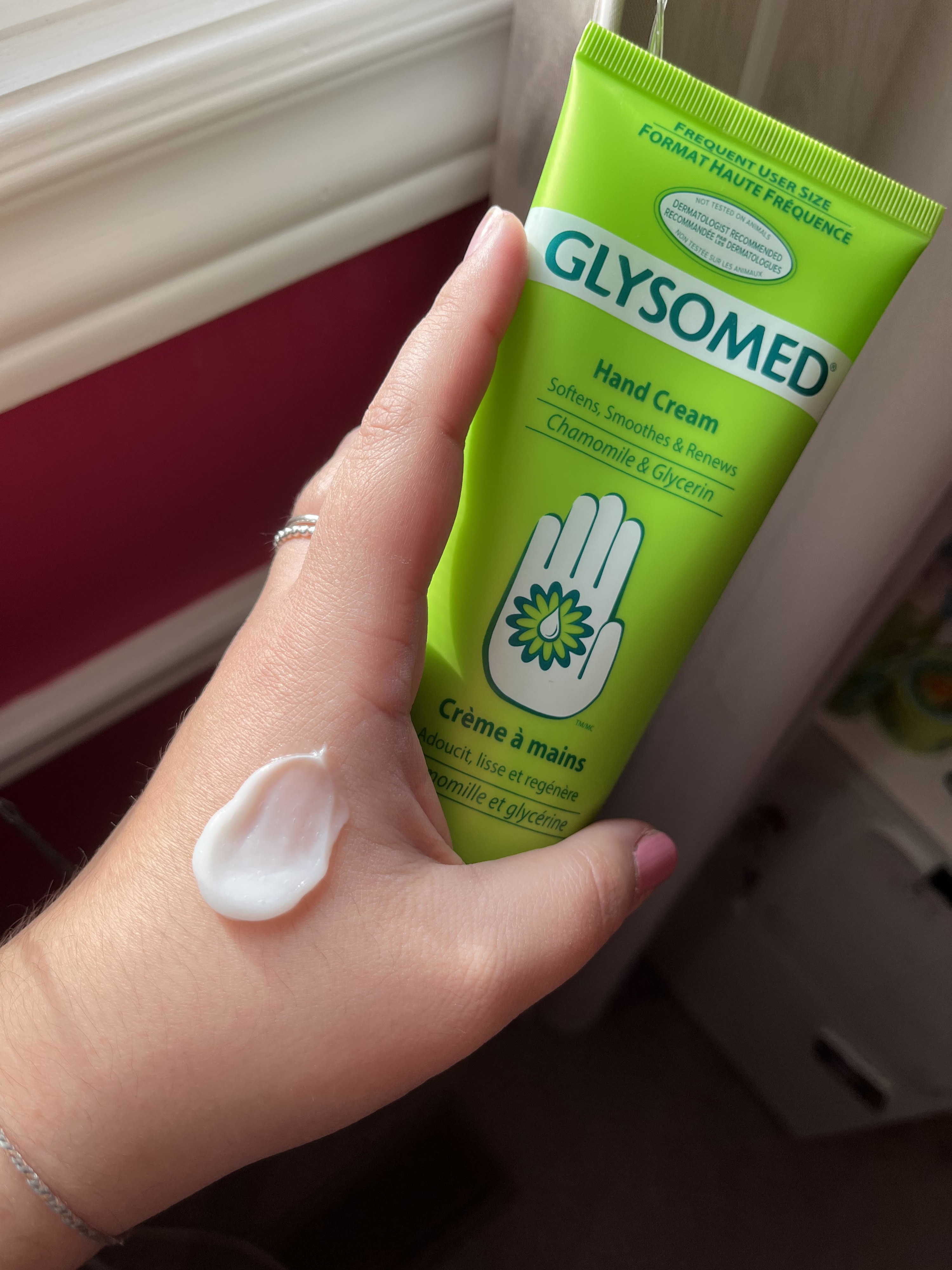 Bianca holding up a tube of the hand cream with a small dollop of it on her hand