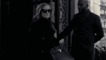 wearing a turtleneck and sunglasses, Anna struts out of her hotel