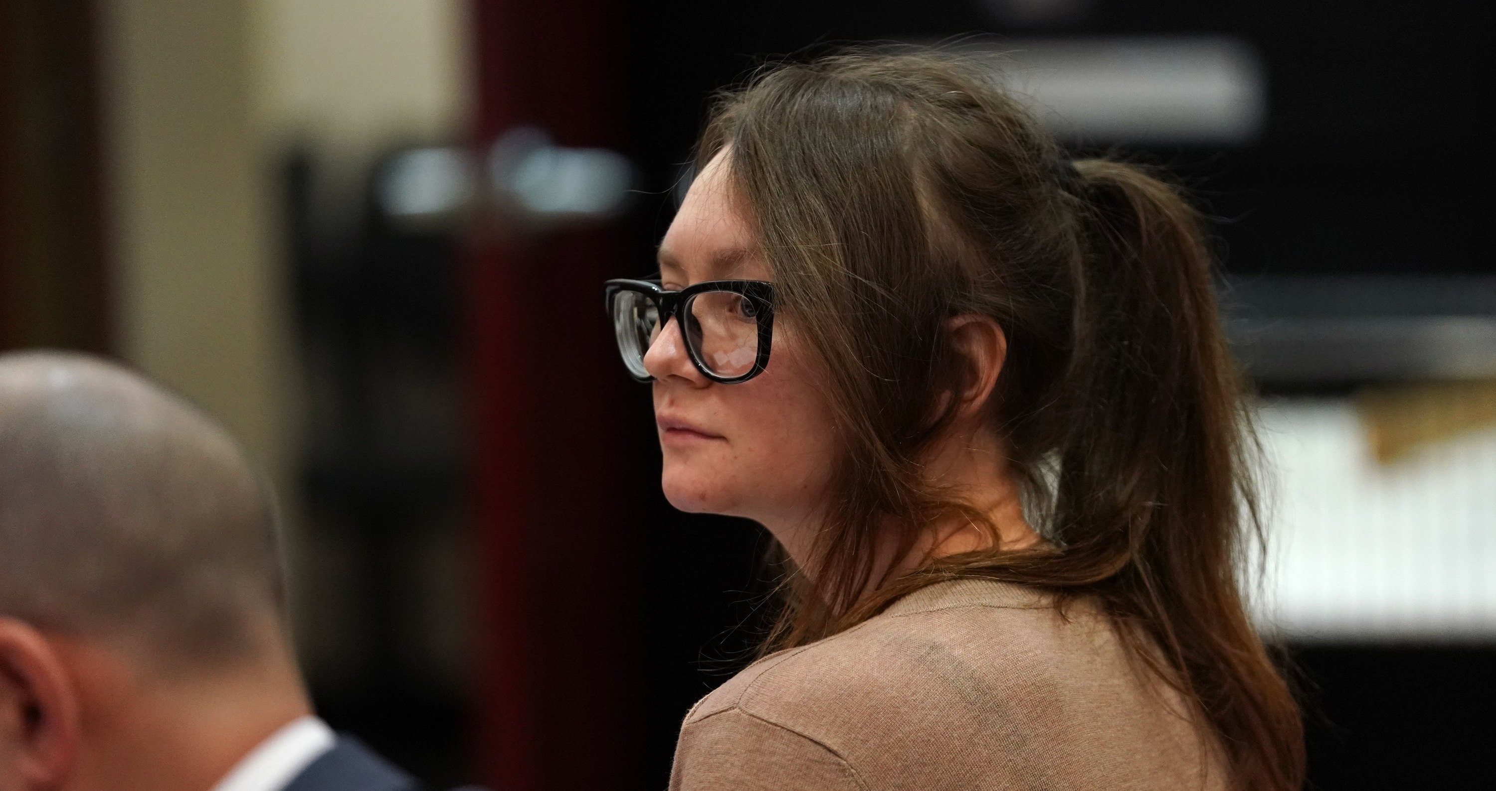 Anna sitting in the courtroom and wearing eyeglasses
