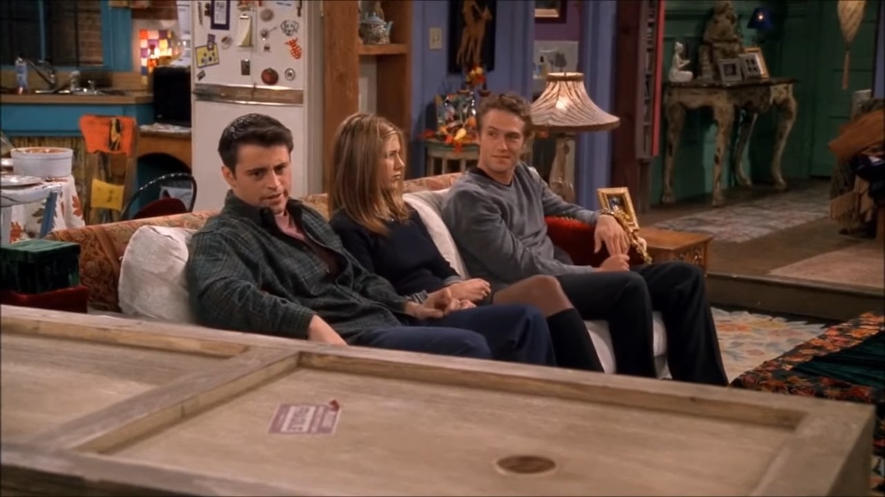 Joey and co. sitting on the couch while Chandler lays in a box in &quot;Friends&quot;