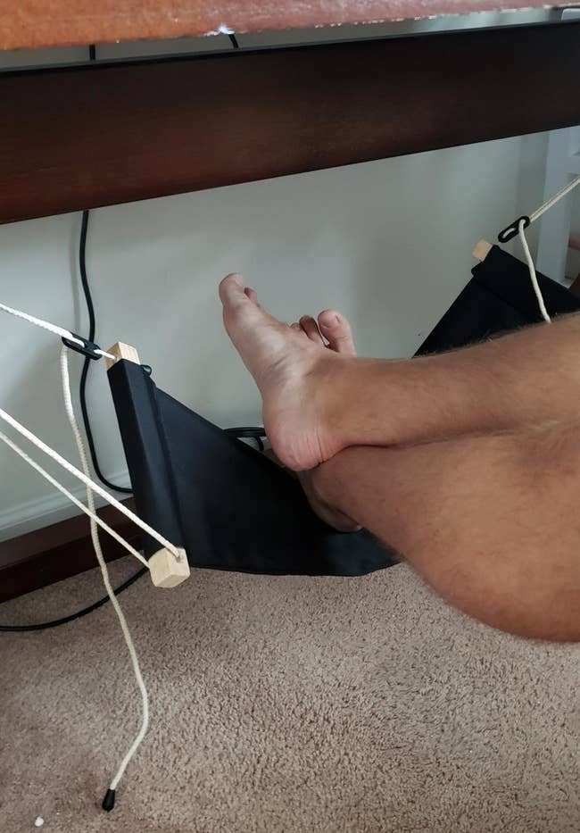 A reviewer resting their feet in a hammock installed under their desk