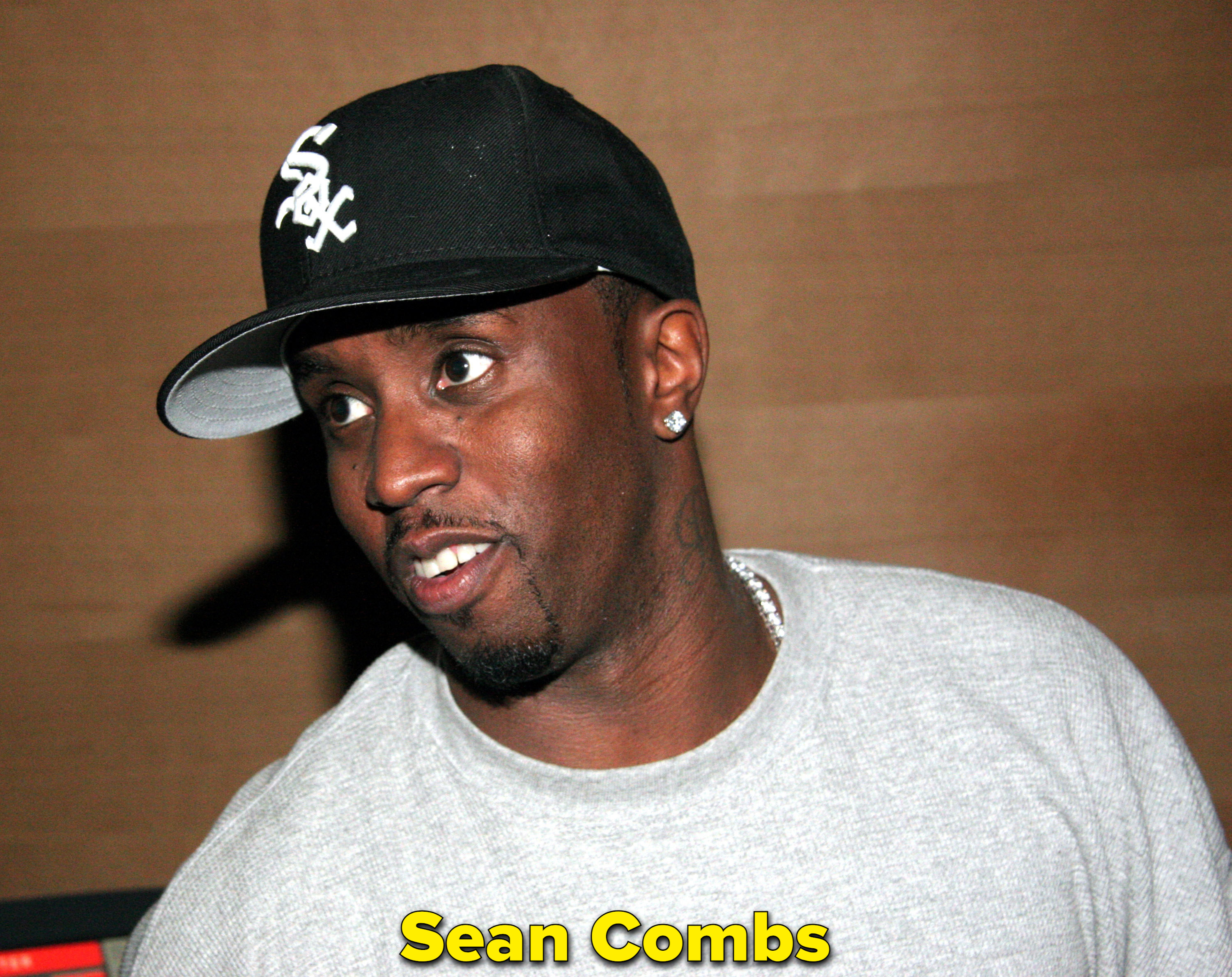 Sean Combs looking to the side in a grey sweater and black Sox hat