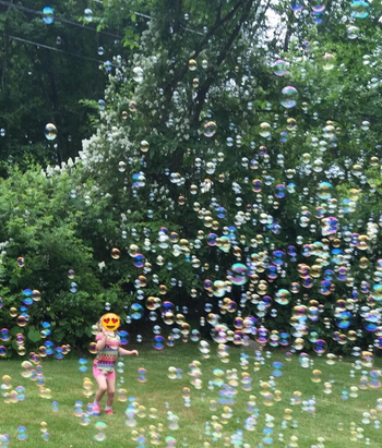 reviewer's photo of their child enjoying the bubbles