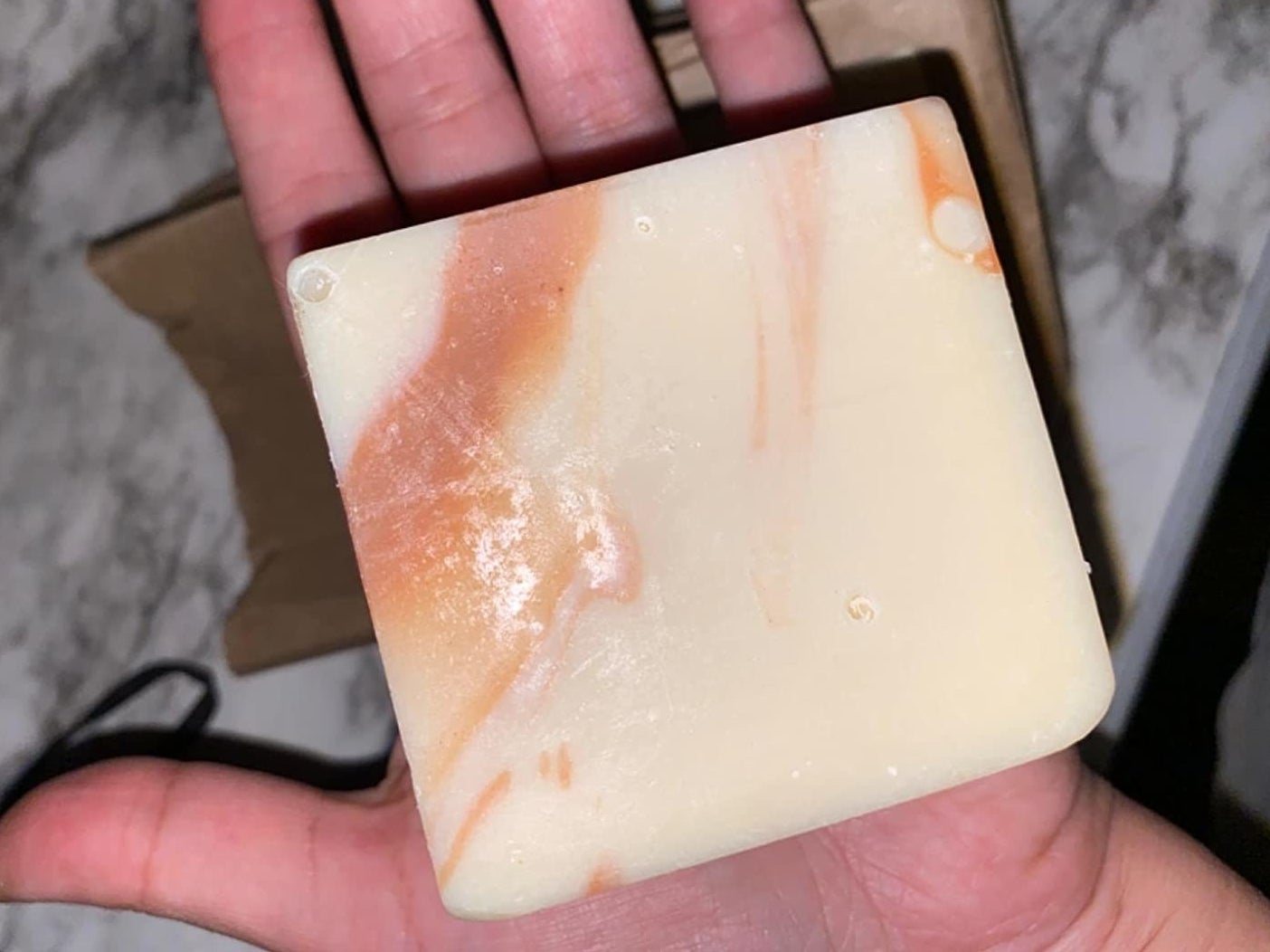 a reviewer holding a square bar of soap