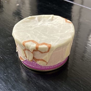 a reviewer photo of a can with bees wax wrapped covering the top